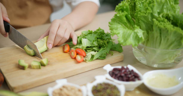 istock Young woman's hands cutting avocado to make salad. 2157033151