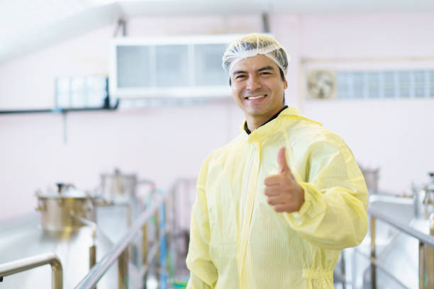 Employee fueling industrial boiler, using a long-handled tool inside a food production facility