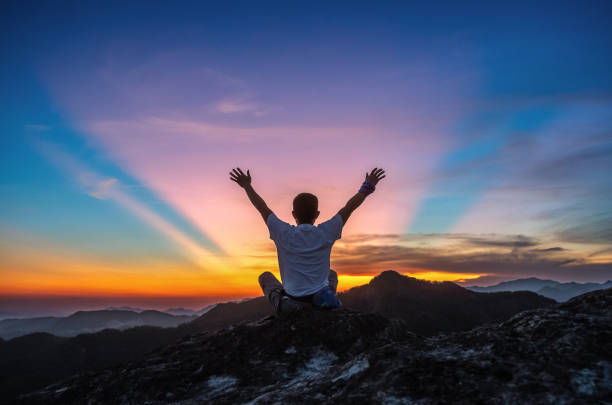 Sitting on the mountaintop waving to the sky and sunset