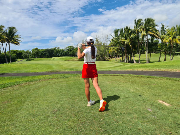 istock Female Golfer Taking a Swing on a Tropical Golf Course 2157035633