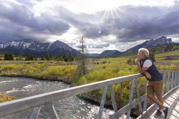 istock Senior man looks out to mountains from bridge 2157035697