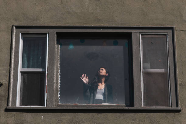 Woman staring out the window during the coronavirus lockdown.