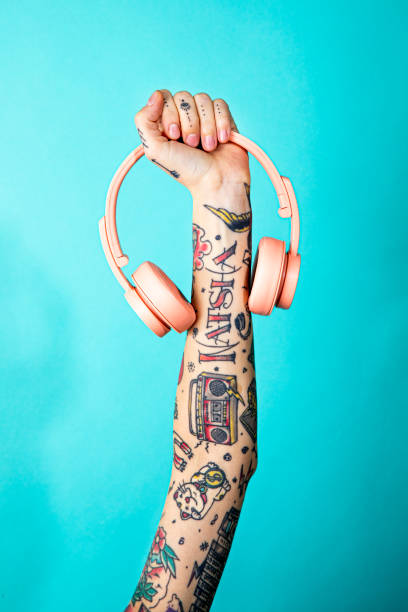 istock Tattooed arm holding a pink headphones 2157042999