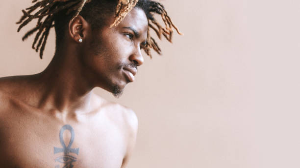 istock Black tattooed man posing by a beige background 2157044438