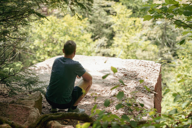 istock A traveler squats by a cliff overlooking the forest 2157045634