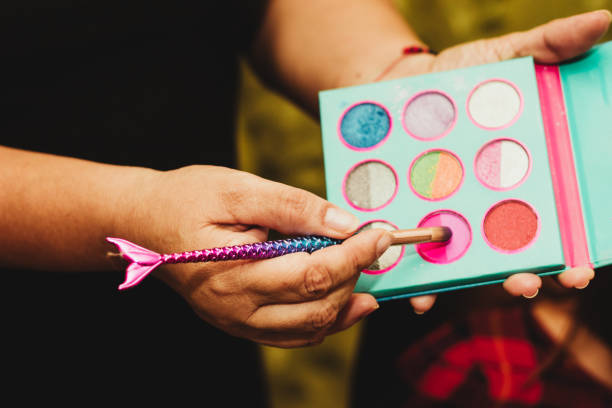 Hand holding colorful makeup palette and mermaid brush for application