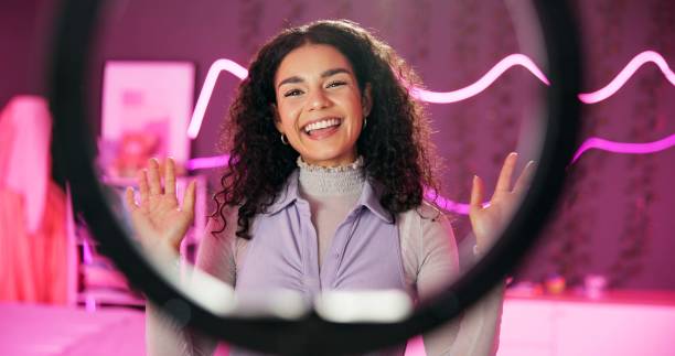 istock Young, woman and talking with ring light for vlog tutorial, influencer with neon in bedroom. Female person, discussion and review for live stream or podcast, content creator with broadcast in home 2157048699