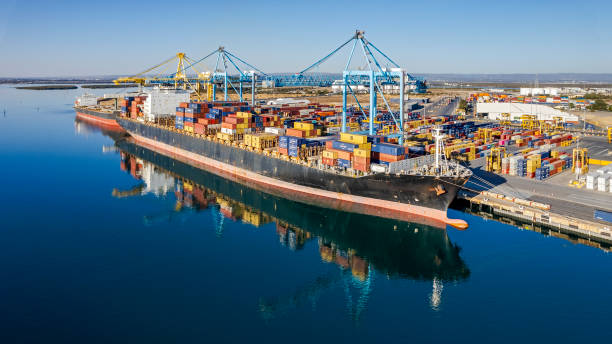 Aerial view large container ship loading/unloading at Port Adelaide, dwarfing bulk carrier behind.