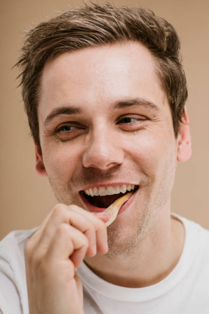 istock Blond man brushing his teeth with a wooden toothbrush 2157057229