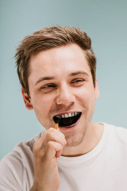 istock Blond man brushing his teeth with a wooden toothbrush 2157057258