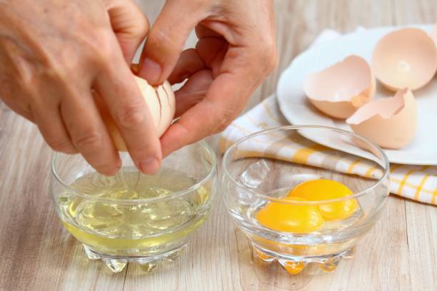Woman hands breaking an egg to separate  egg white and  yolk.