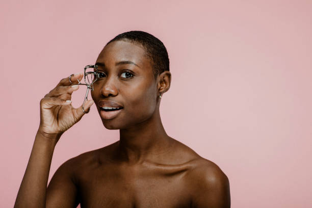 istock Cheerful black female beauty blogger using an eyelash curler 2157060029