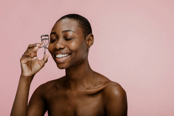 istock Cheerful black female beauty blogger using an eyelash curler 2157060036