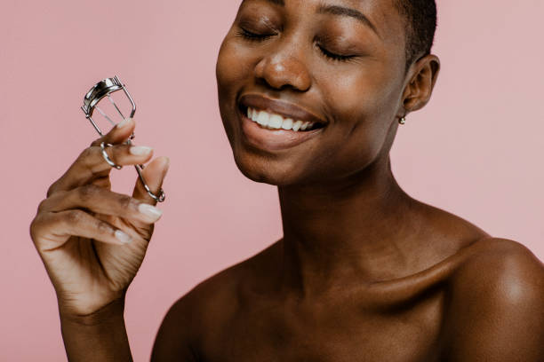 istock Cheerful black female beauty blogger using an eyelash curler 2157060039