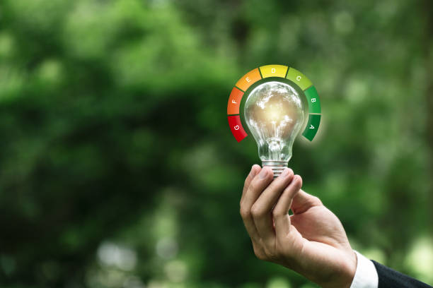 istock Hand hold light bulb with energy efficient rating. Energy saving rate for reduce carbon footprint.Save cost green energy. Net zero. Renewable energy sources. Green House. 2157062177
