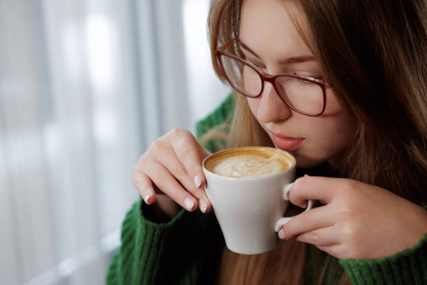 istock A woman with eyeglasses is sipping coffee from a cup 2157064738