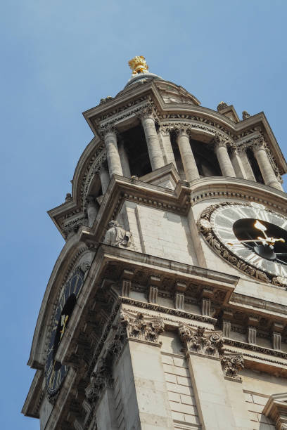 istock Clock tower with multiple clocks with a golden statue on top, viewed from below 2157065220