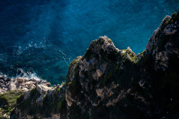 Large Rock formations and forest-covered mountain cliffs near blue ocean water