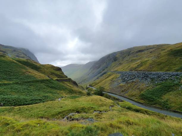 istock Scenic road through lush green valley with rolling hills on each side 2157065665
