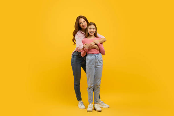 istock Mother and daughter hugging on yellow background 2157066171