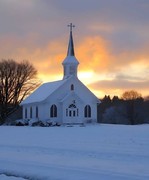 Rear view of a mid adult man sitting alone on a wooden pew inside an Anglican church in winter. The man is deep in thought and prayer. Beyond him, near the altar, an illuminated Christmas tree - adorned with colorful lights - is defocused. The man wears a warm winter puffer jacket. Room for copy space.