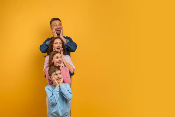 istock Surprised Family Posing Playfully Against Yellow Background in a Studio 2157066313