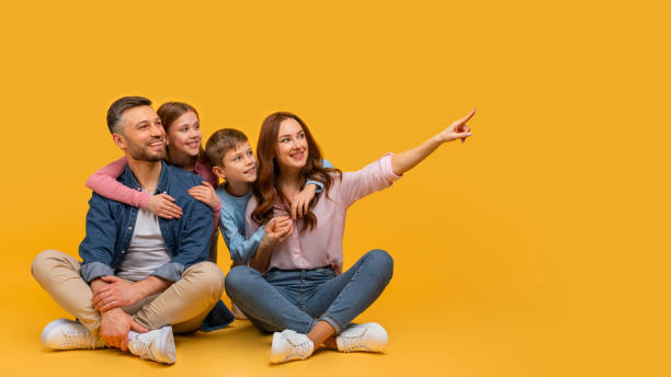istock Family Sitting on the Floor Pointing at Something 2157066450
