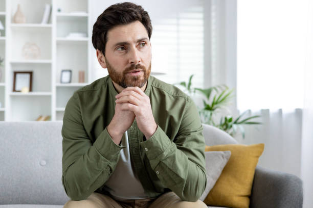 istock Thoughtful man sitting on a sofa in a modern living room 2157070539