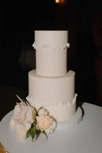 istock a three tier white cake on a silver tablecloth with a few flowers 2157071959