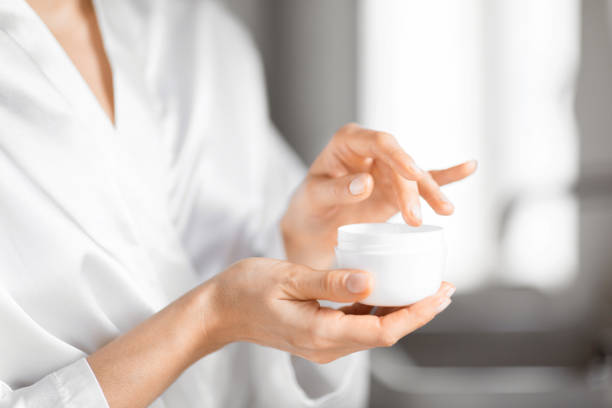 istock Close-up of hands applying cream from jar 2157073057