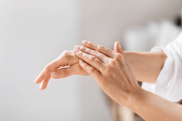 istock Woman in white robe applying hand cream 2157073068