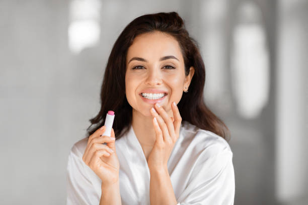 istock Joyful beautiful woman applying lipstick in bathrobe 2157073082
