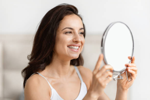 istock Smiling young woman looking into handheld mirror 2157073133