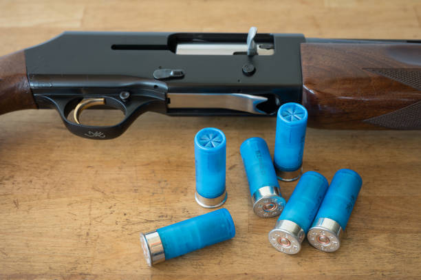 Detail of a 12 gauge semi-automatic shotgun and some shotshells on a wooden table