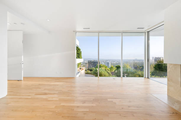 istock Modern living room with hardwood floors, expansive window showcasing tree view 2157074048
