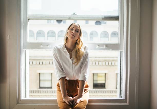 istock Woman sitting on a window sill 2157074557