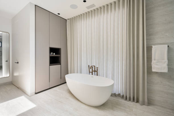 istock Spacious bathroom with a white bathtub and beige curtains 2157074766