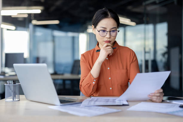 istock Focused businesswoman reviewing documents in modern office 2157077084