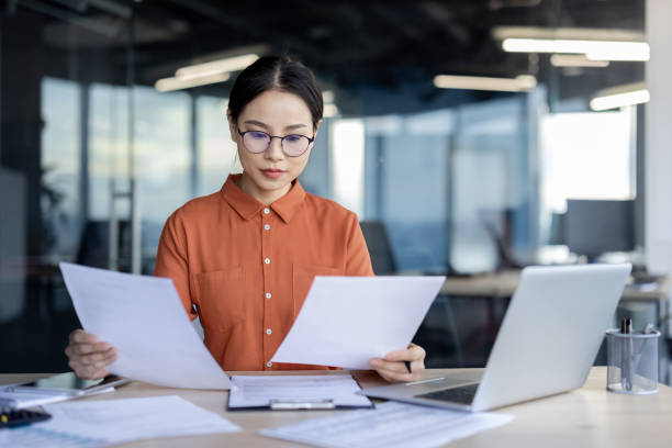 Focused professional woman examining business documents in a modern office