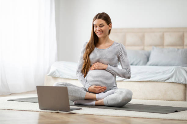 istock Pregnant woman practicing yoga at home, watching video lesson 2157077855