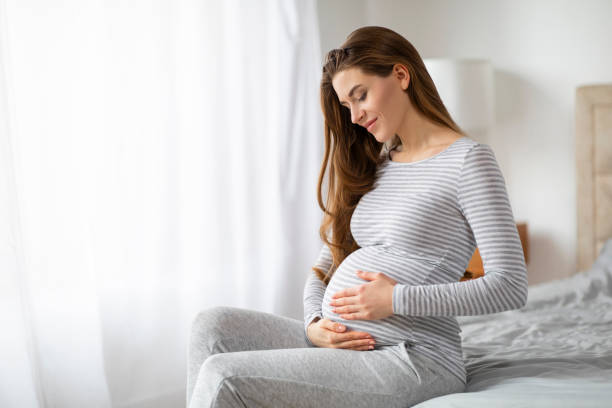 Expectant mother sitting thoughtfully at home, copy space