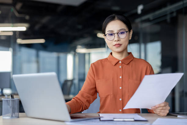 istock Focused businesswoman analyzing documents at her modern office desk 2157078360