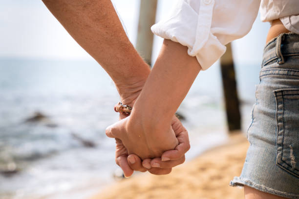 istock Unrecognizable couple holding hands looking at the sea 2157079979