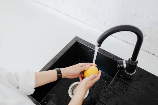 istock Woman rinsing a yellow lemon in a sink 2157082279