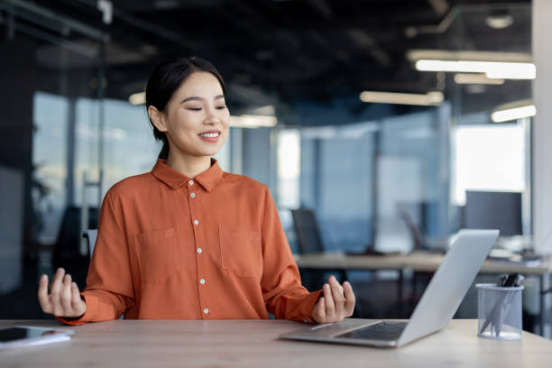 istock Young businesswoman meditating and practicing mindfulness at work in modern office 2157082376
