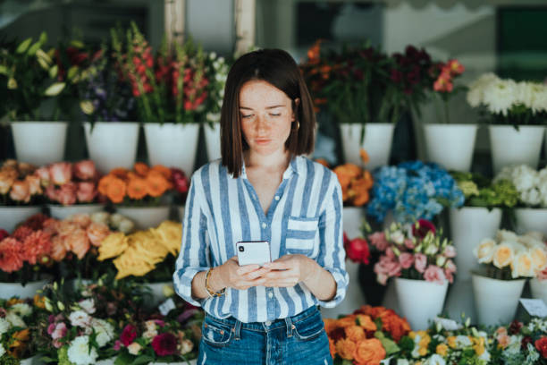 Woman using a phone in front of a flower shop