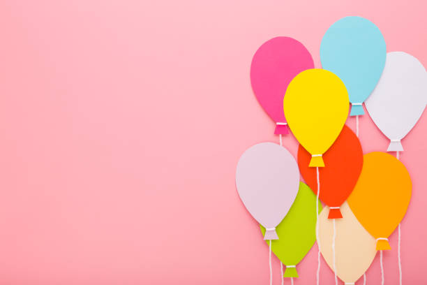 istock Colorful balloon shapes from application paper with white strings on light pink table background. Pastel color. Closeup. Empty place for inspirational text, quote or sayings. Top down view. 2157085043
