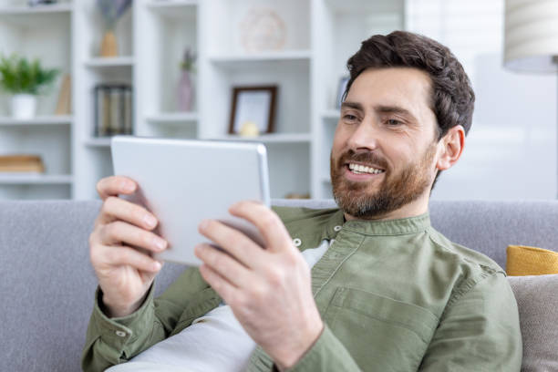 istock Smiling man using digital tablet in modern living room at home 2157085983