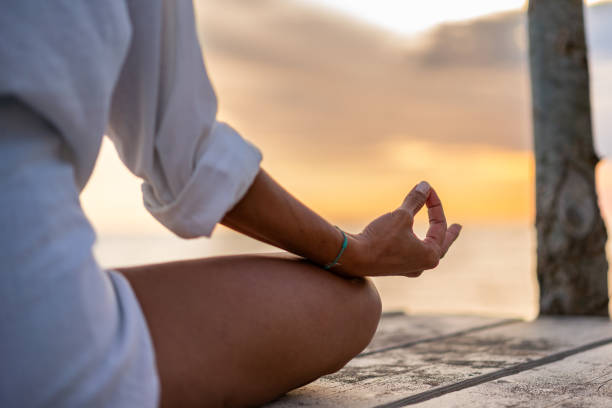 istock Unrecognizable woman sitting alone and meditating on the beach 2157086557