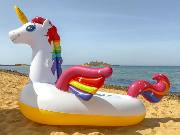 istock Funny inflatable unicorn ring on sandy beach near sea. 2157088097